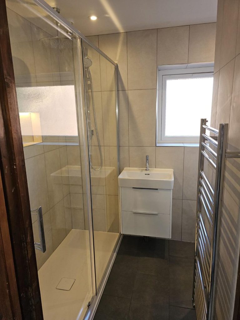 Compact bathroom featuring glass shower and sink.