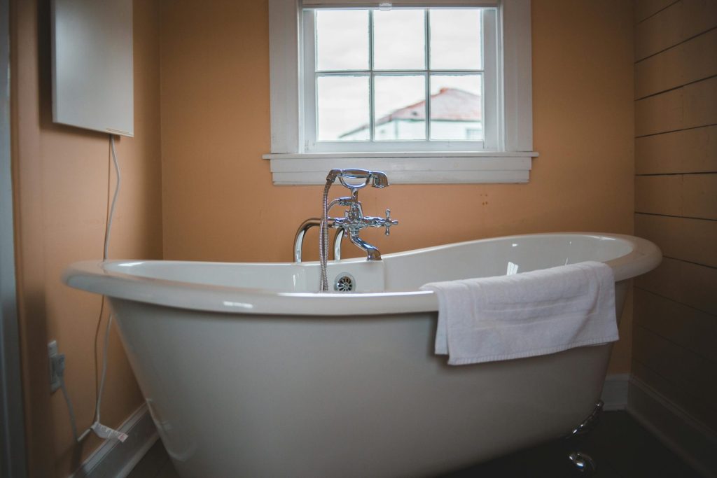 Freestanding bathtub against soft peach wall backdrop